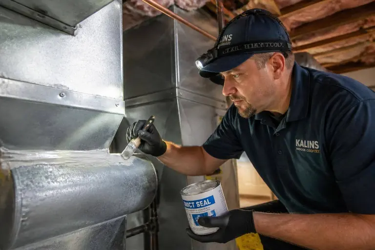 Technician sealing a duct joint with mastic