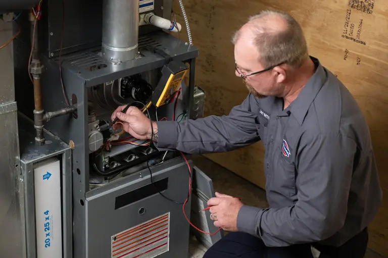 Technician testing furnace controls with a meter